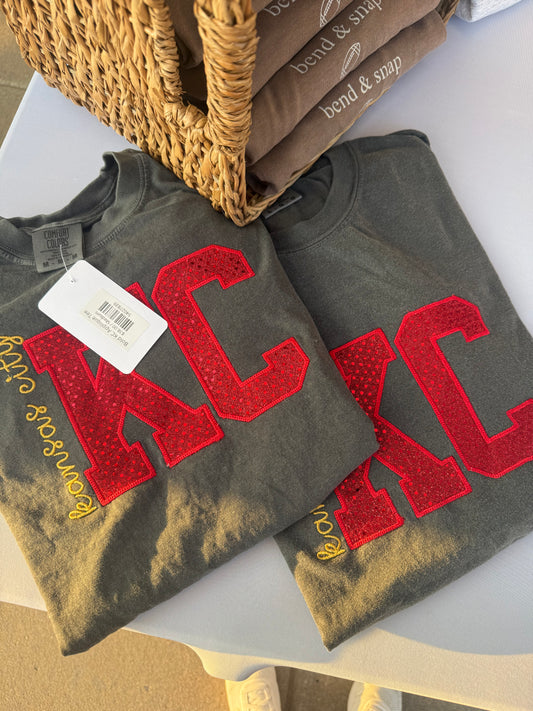 a pair of grey t-shirts with red letters on them