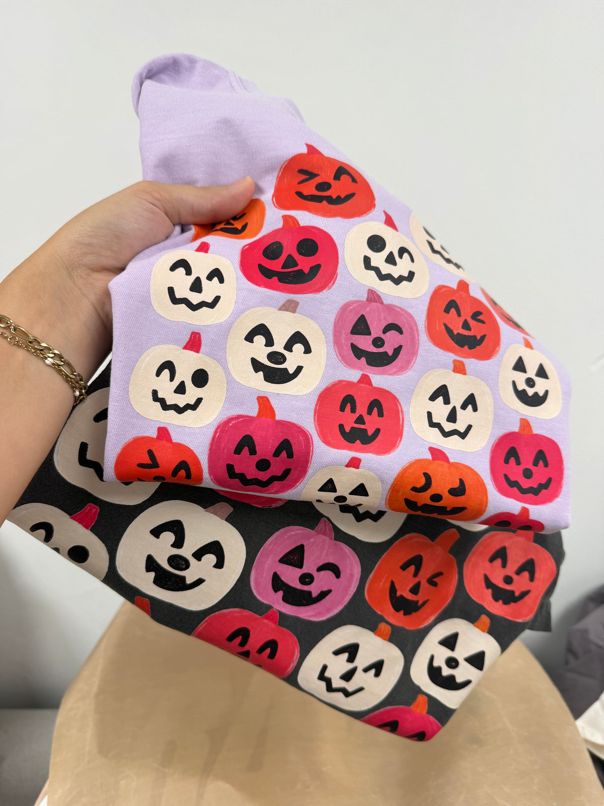 a hand holding a folded towel with pumpkins