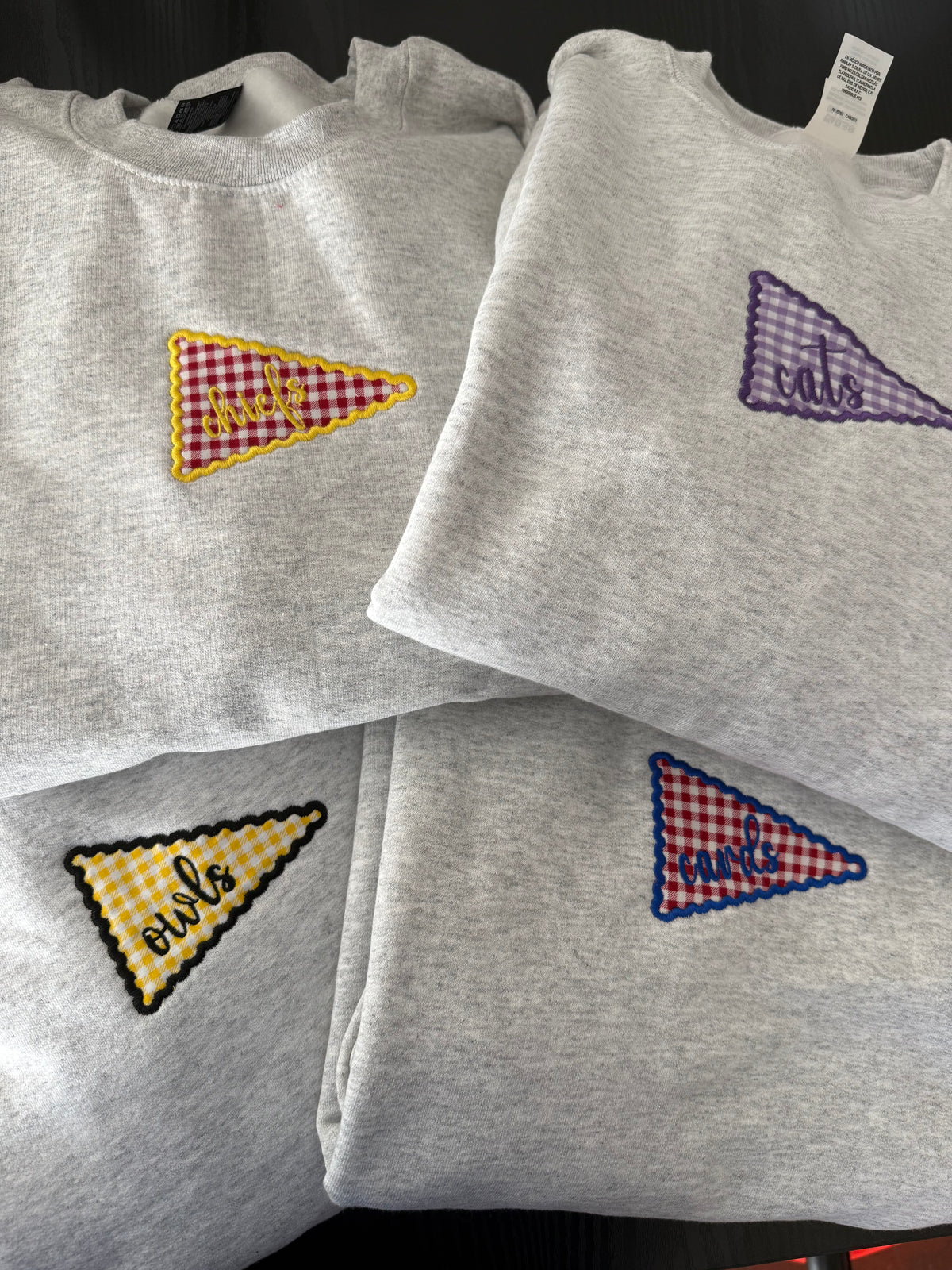 a group of grey shirts with embroidered triangles