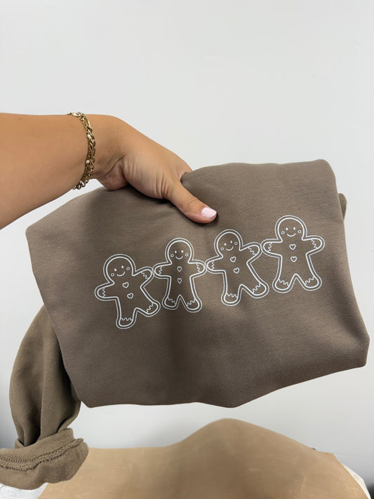 a person holding a brown sweater with gingerbread men on it