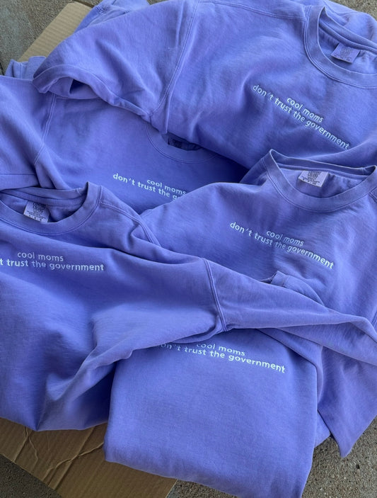 a pile of purple shirts with white text