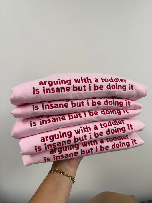 a hand holding a stack of pink sweaters with text